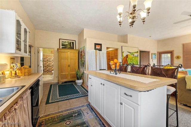 kitchen featuring pendant lighting, dishwasher, a kitchen breakfast bar, light tile patterned floors, and white cabinetry