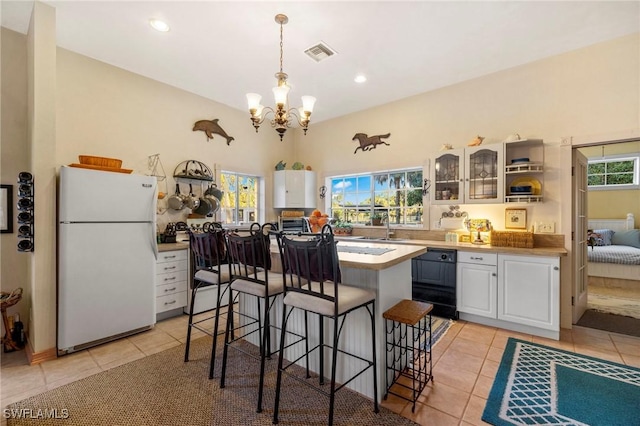 kitchen featuring a kitchen breakfast bar, light tile patterned floors, decorative light fixtures, white cabinets, and white fridge