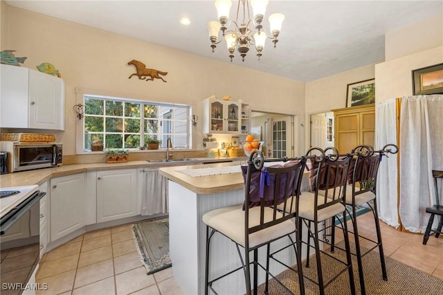 kitchen featuring white cabinets, hanging light fixtures, a breakfast bar area, and sink