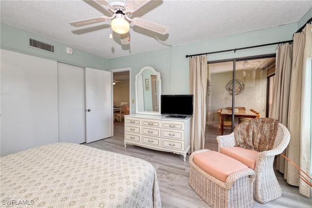 bedroom featuring a textured ceiling, light hardwood / wood-style flooring, a closet, and ceiling fan