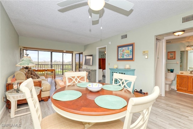 dining space featuring a textured ceiling, ceiling fan, and light hardwood / wood-style flooring