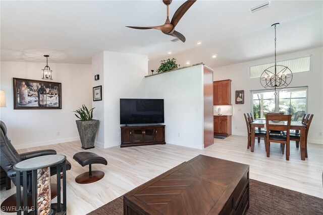 living room featuring light hardwood / wood-style floors and ceiling fan with notable chandelier