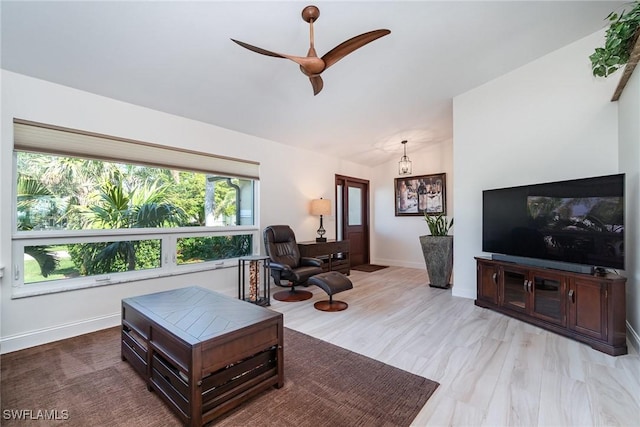 living room with ceiling fan, light hardwood / wood-style floors, and vaulted ceiling