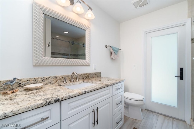 bathroom featuring vanity, toilet, and a shower with shower door