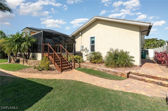 rear view of house featuring a lanai and a lawn