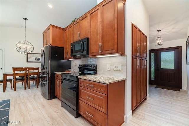 kitchen featuring black appliances, hanging light fixtures, tasteful backsplash, light stone counters, and a chandelier