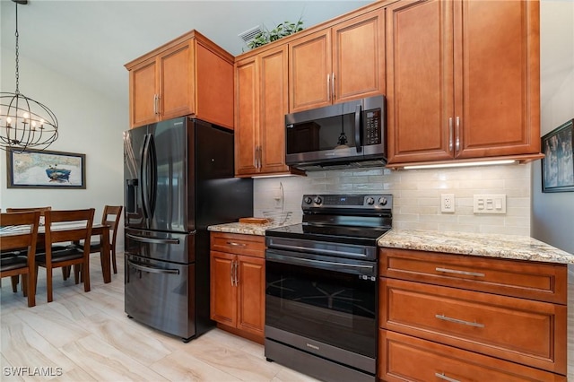 kitchen featuring pendant lighting, light stone countertops, appliances with stainless steel finishes, tasteful backsplash, and a notable chandelier