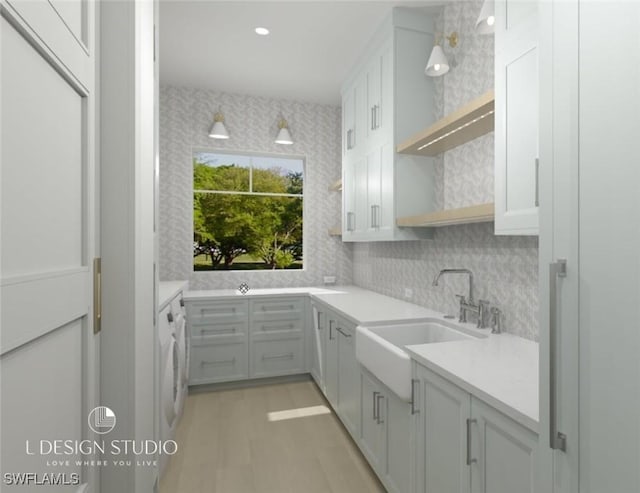 kitchen with sink, hanging light fixtures, backsplash, washer / dryer, and light wood-type flooring