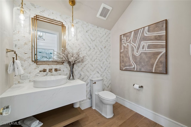 187 10th Ave S, Naples, FL 34102 - bathroom with wood finished floors, toilet, vaulted ceiling, vanity, and baseboards
