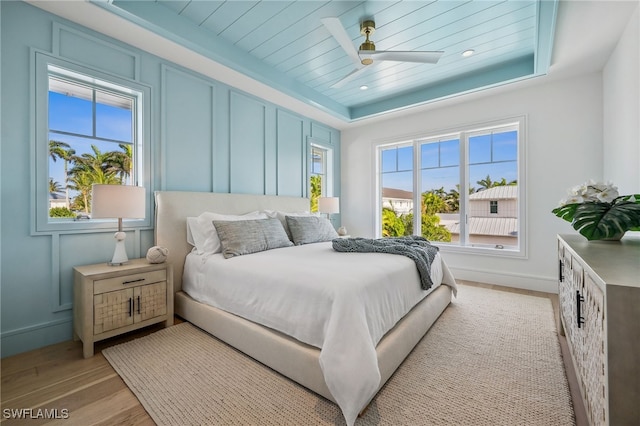 187 10th Ave S, Naples, FL 34102 - bedroom featuring light wood-style floors, baseboards, a raised ceiling, a ceiling fan, and a decorative wall
