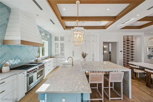 187 10th Ave S, Naples, FL 34102 - kitchen with a sink, range with two ovens, a chandelier, a large island, and white cabinets