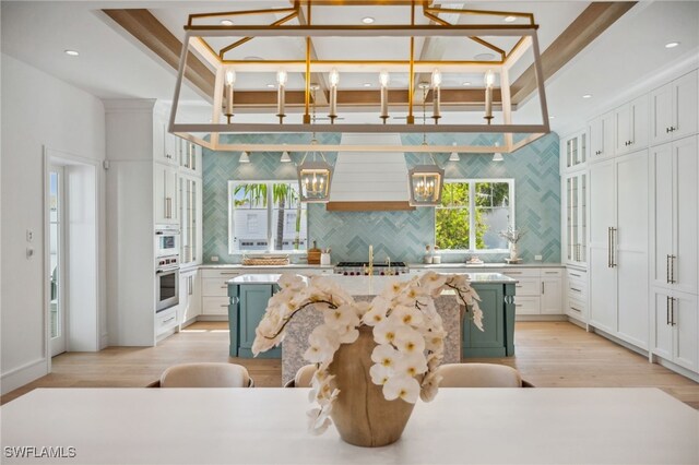 187 10th Ave S, Naples, FL 34102 - kitchen featuring a chandelier, light wood-type flooring, backsplash, a center island, and white cabinets