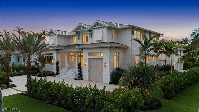 187 10th Ave S, Naples, FL 34102 - view of front facade with an attached garage, a standing seam roof, metal roof, decorative driveway, and a lawn