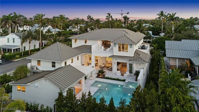 187 10th Ave S, Naples, FL 34102 - back of house at dusk with a balcony, a standing seam roof, metal roof, outdoor lounge area, and a patio area