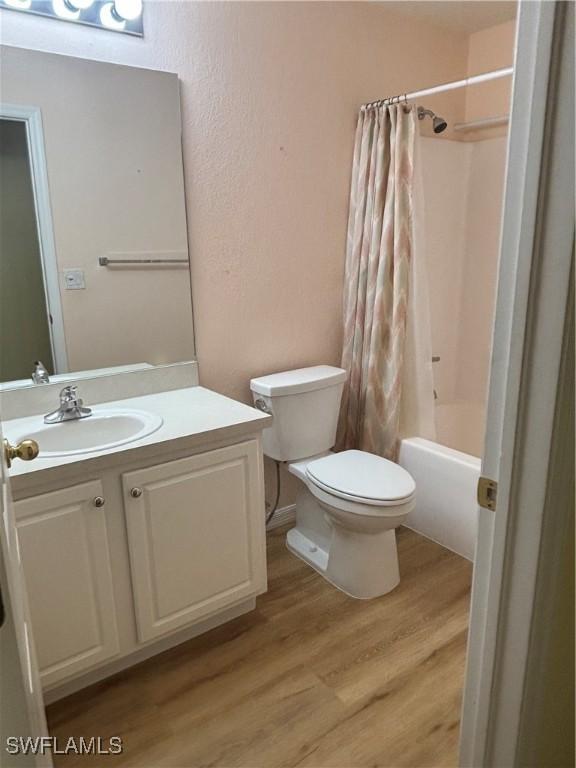 full bathroom with wood-type flooring, toilet, vanity, and shower / bath combo with shower curtain