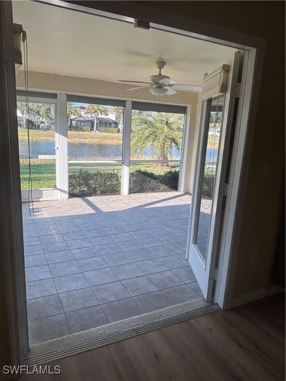 unfurnished sunroom with a water view and ceiling fan