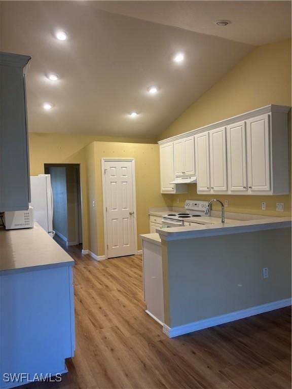 kitchen with white appliances, lofted ceiling, kitchen peninsula, and white cabinets