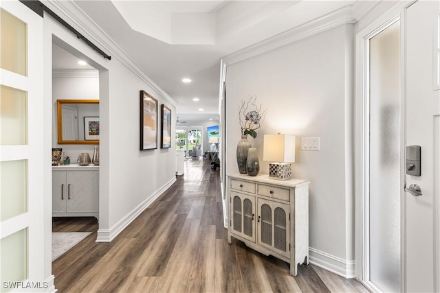 hallway featuring a barn door, ornamental molding, dark wood-style flooring, and recessed lighting