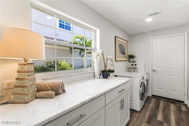 washroom featuring cabinet space, dark wood-style floors, visible vents, and separate washer and dryer