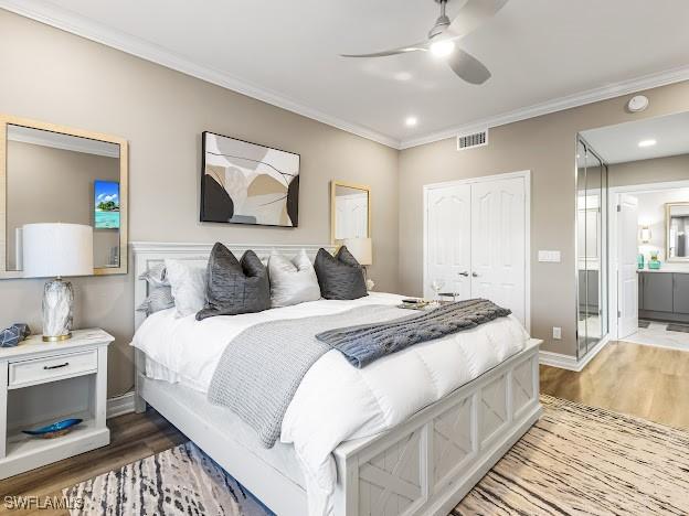 bedroom featuring a closet, wood finished floors, visible vents, and crown molding