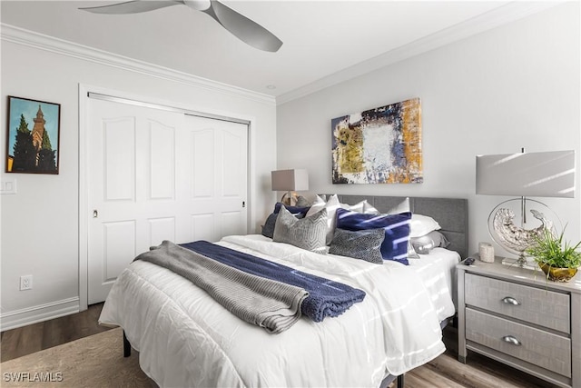 bedroom featuring dark wood-type flooring, a ceiling fan, baseboards, a closet, and crown molding