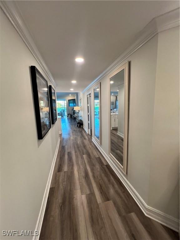 hallway featuring ornamental molding, dark wood-type flooring, recessed lighting, and baseboards