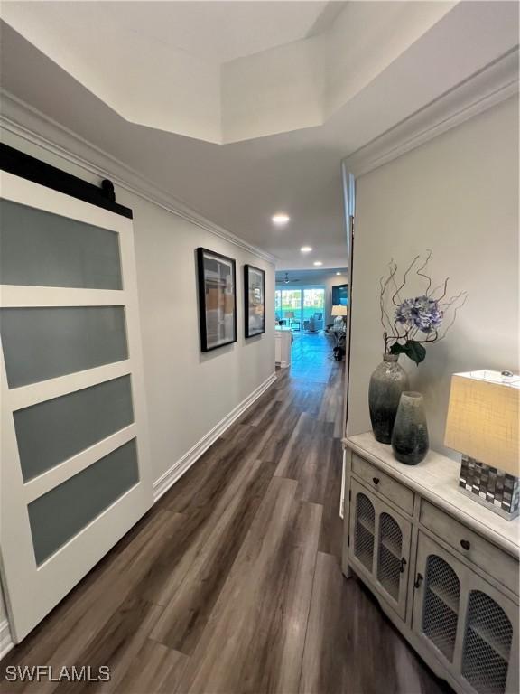 hall with crown molding, recessed lighting, a barn door, dark wood-type flooring, and baseboards