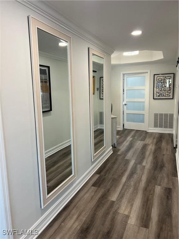 corridor featuring ornamental molding, visible vents, dark wood finished floors, and baseboards