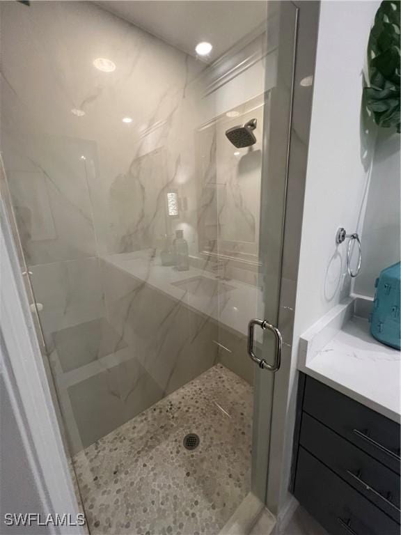 full bath featuring a marble finish shower and vanity