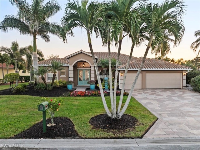 mediterranean / spanish-style house featuring french doors, a garage, and a lawn