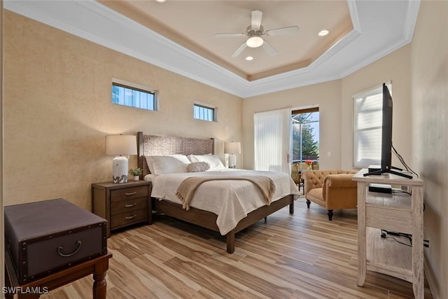 bedroom featuring a raised ceiling, ornamental molding, ceiling fan, and light hardwood / wood-style flooring