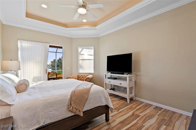 bedroom featuring a tray ceiling, light hardwood / wood-style flooring, ornamental molding, and ceiling fan