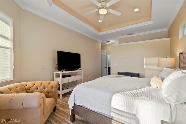 bedroom with crown molding, ceiling fan, a tray ceiling, and light hardwood / wood-style floors