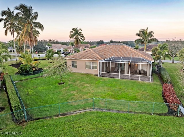 back house at dusk featuring a yard and a lanai