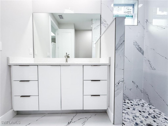 bathroom with a tile shower and vanity