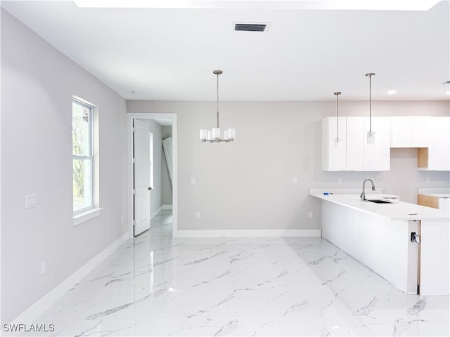 kitchen with sink, white cabinetry, and hanging light fixtures