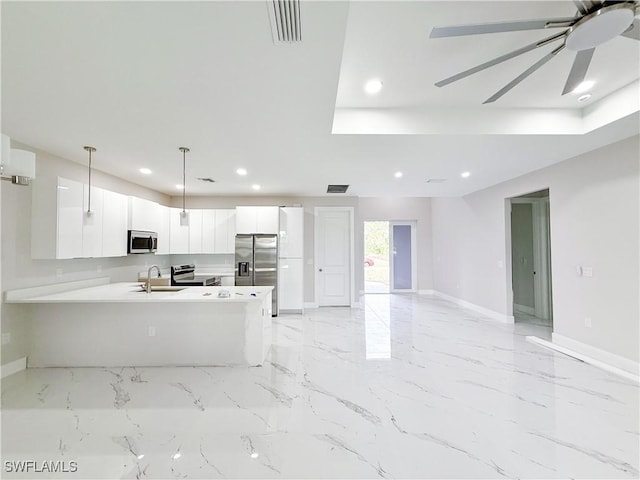 kitchen featuring appliances with stainless steel finishes, kitchen peninsula, pendant lighting, white cabinets, and sink