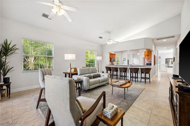 living room with lofted ceiling, ceiling fan, and light tile patterned floors