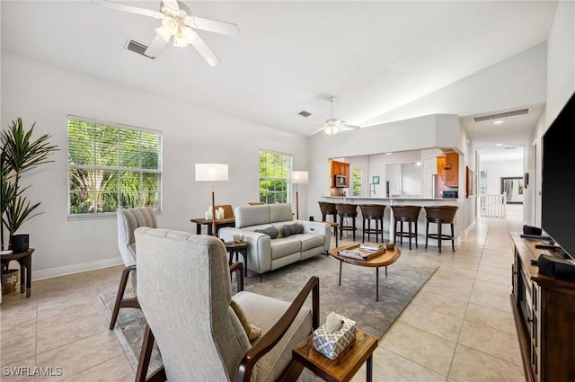 living room with ceiling fan, visible vents, light tile patterned floors, and lofted ceiling