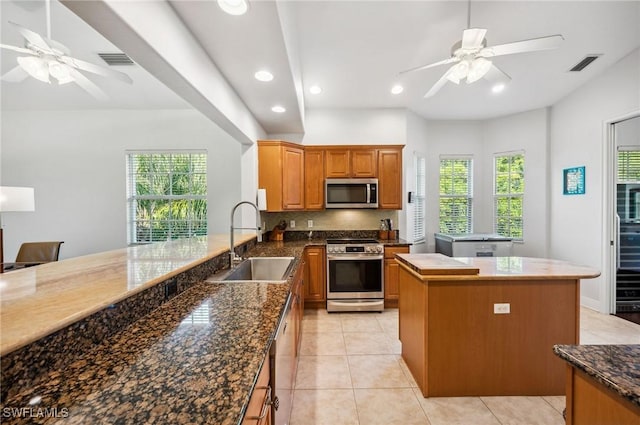 kitchen featuring sink, decorative backsplash, appliances with stainless steel finishes, light tile patterned flooring, and kitchen peninsula