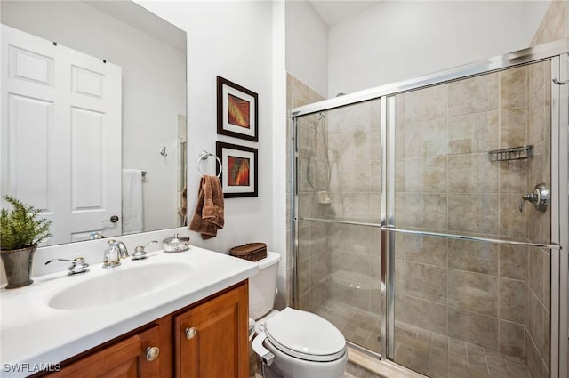 bathroom featuring vanity, toilet, and a shower with door