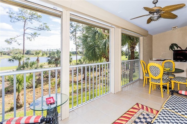 sunroom / solarium featuring ceiling fan and a water view