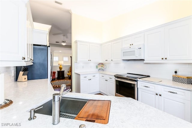 kitchen featuring white cabinets, appliances with stainless steel finishes, decorative backsplash, and sink