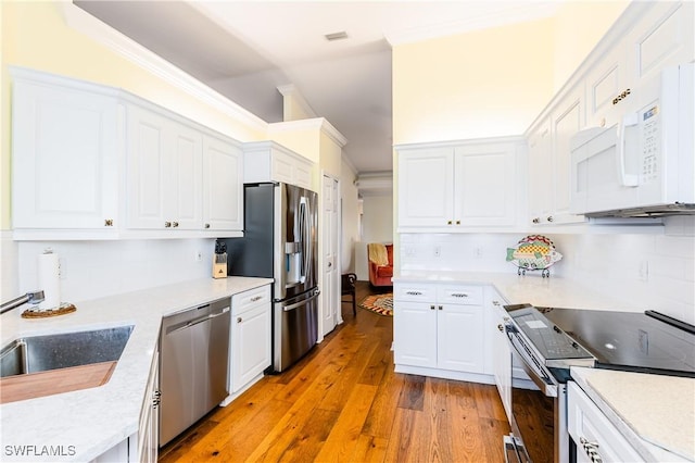 kitchen featuring white cabinets, stainless steel appliances, crown molding, and light hardwood / wood-style floors