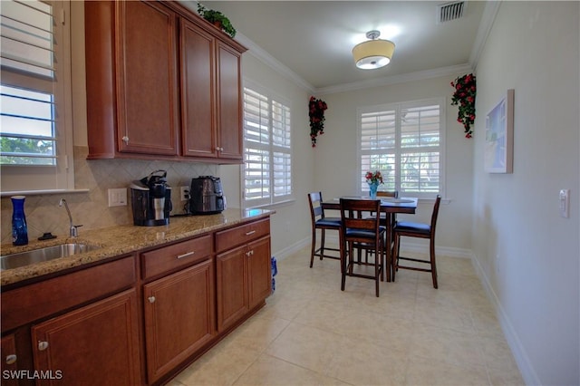 kitchen featuring decorative backsplash, crown molding, sink, and light stone counters