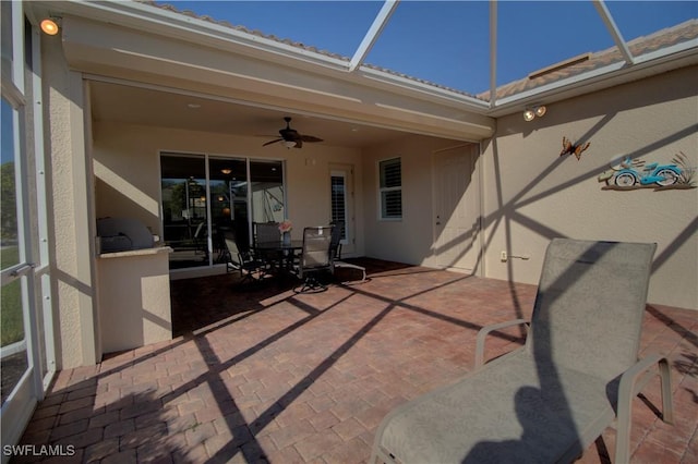 view of patio / terrace featuring ceiling fan and glass enclosure