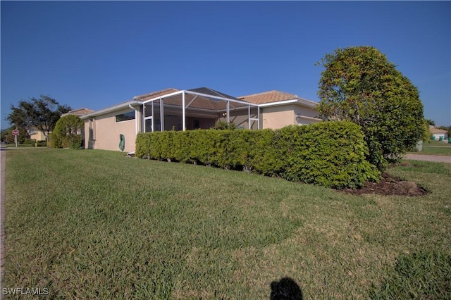 view of side of property featuring a lawn and a lanai