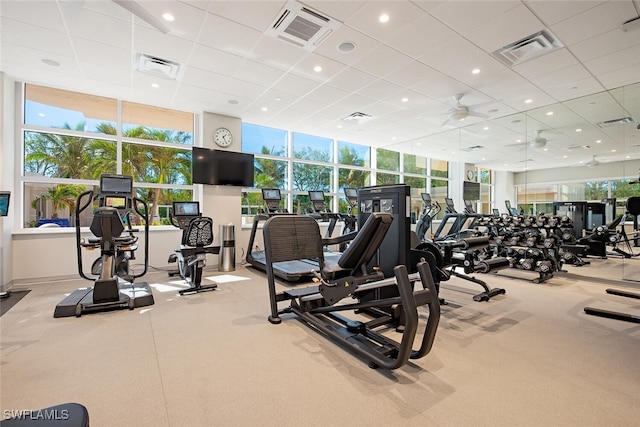 exercise room with ceiling fan and a drop ceiling