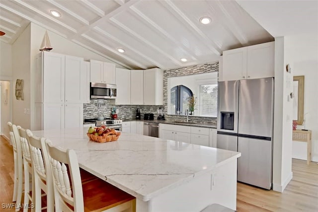 kitchen featuring light stone countertops, white cabinets, backsplash, and appliances with stainless steel finishes