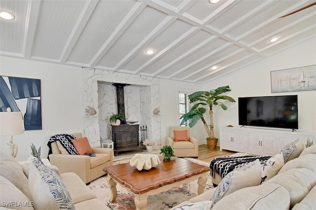 living room featuring lofted ceiling, a wood stove, and hardwood / wood-style flooring